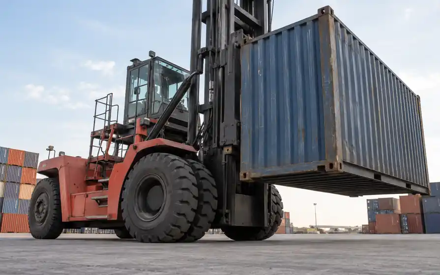 Large tyres on a port container handler with its vertical lifting mast visible.